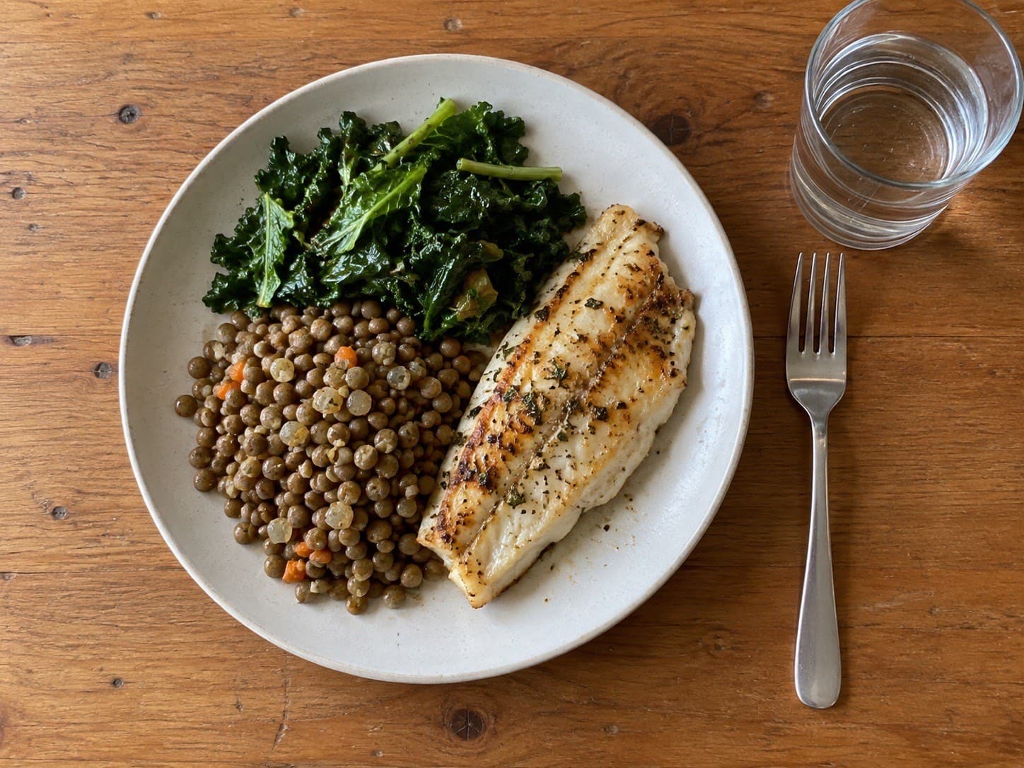 A high-protein meal of grilled white fish, lentils and kale, plated for eating well on weight loss injections